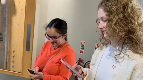 two women looking at their phones