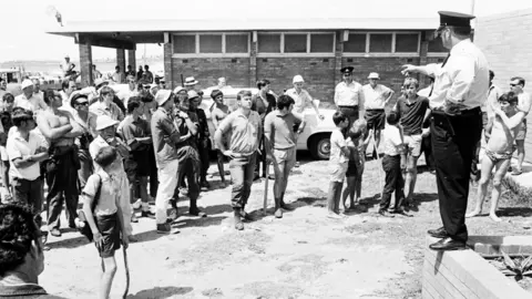 Getty Images A policeman directs a crowd of officers and volunteers at Fairy Meadow beach