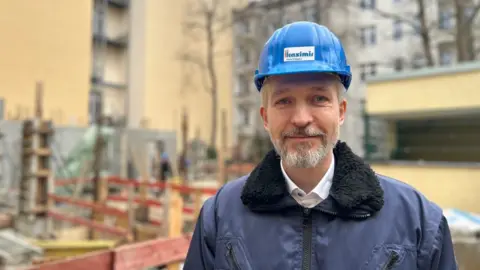 André Kasimir wearing a blue hard hat on a building site
