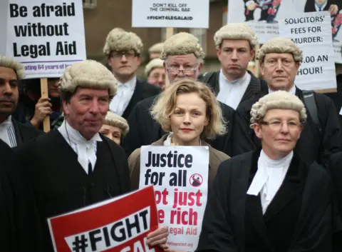 Getty Images legal aid protest actress maxine peake with barristers in wigs and gowns. sign reads justice for all, not just the rich