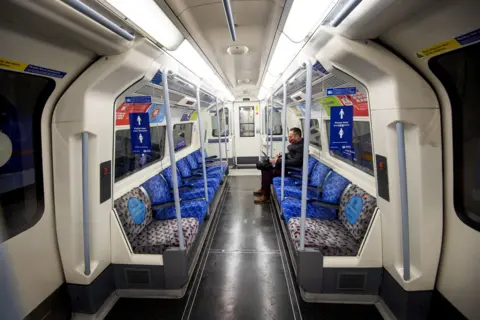 Victoria Jones / PA Media A commuter travelling on a deserted Jubilee Line London Underground train