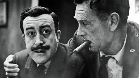 Getty Images Sterling Hayden (right) as General Jack Ripper, holds a cigar in his mouth and puts his arm around Peter Sellers, as Group Captain Lt. Mandrake, in a still from the Stanley Kubrick directed film Dr. Strangelove: Or How I Came to Stop Worrying and Love the Bomb