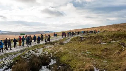 Martin Hampton Line of people hiking across Dartmoor.