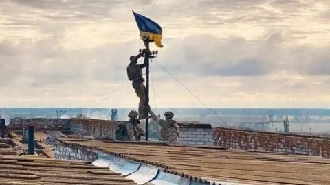 K.Tymoshenko/Facebook Soldiers hoisting Ukrainian flag - reportedly over Vysokopillya