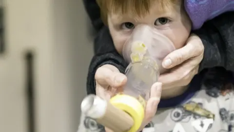 Getty Images boy with asthma using a spacer device