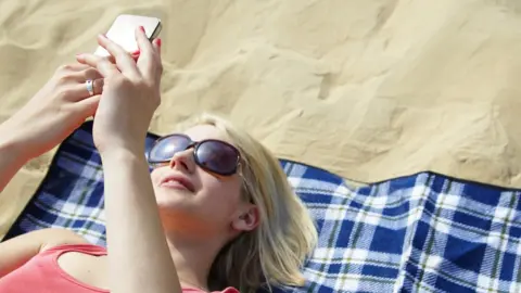 Getty Images Woman lies on beach on towel