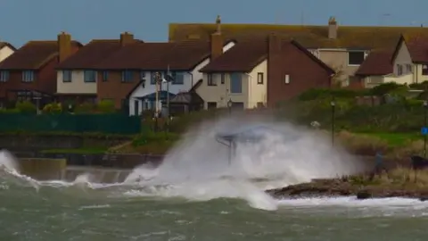 BBC Weather Watchers / Ribster13 Waves and white foam shooting up onto the land in front of a cluster of houses