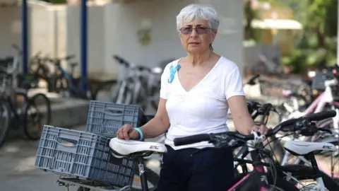 Women Wage Peace Vivian Silver in white T-shirt among bicycles