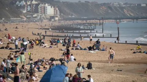 PA Media People enjoy the warm weather on Bournemouth beach in Dorset.