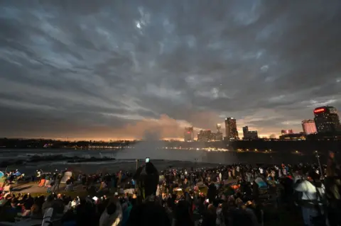 ANGELA WEISS/Getty images The sky darkens as people watch during totality of the total solar eclipse across North America, at Niagara Falls State Park in Niagara Falls, New York, on April 8, 2024.