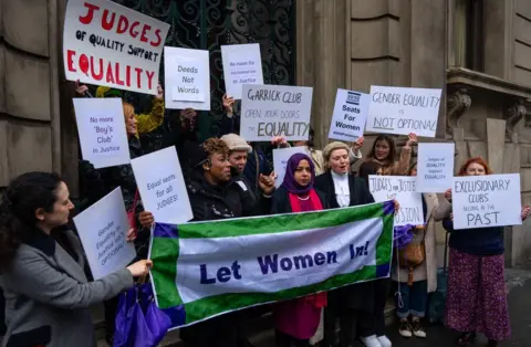 Getty Images Female protesters holding signs outside the Garrick Club