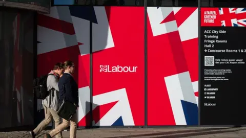 EPA People walk past posters of the Labour Party Annual Conference 2022 in Liverpool, U