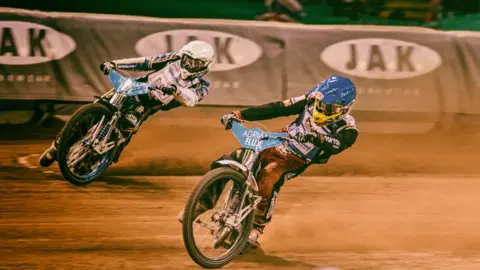 Speedway riders racing on bikes
