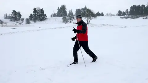 PA Media A man trekking through the snow in Gleneagles