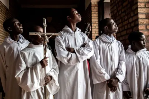 AFP Altar boys try to get a glimpse at the current President of the Democratic Republic of the Congo, Felix Tshisekedi, ahead of a mass at the Notre dame de Kinshasa to commemorate the death of his father, Etienne Tshisekedi on February 1, 2019 in Kinshasa.