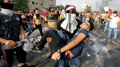 Reuters A man carries away an injured protester in Baghdad, Iraq (2 October 2019)