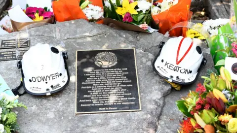 EPA Helmets of Andrew O'Dwyer and Geoffrey Keaton and flowers on their memorial at the Horsley Park fire brigade