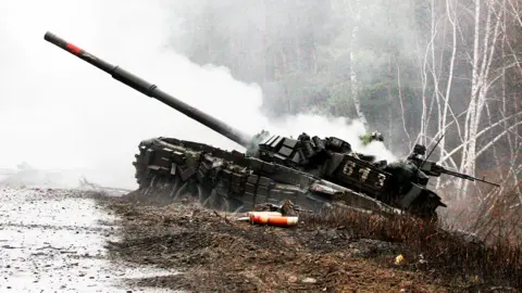 Getty Images Smoke rises from a destroyed Russian tank in Ukraine, 26 February