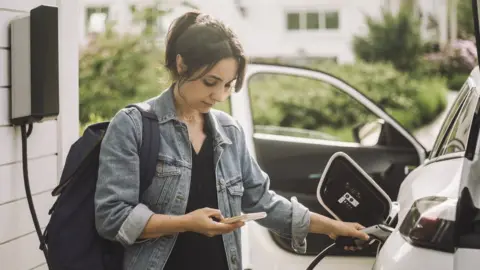 Getty Images Woman charging electric car