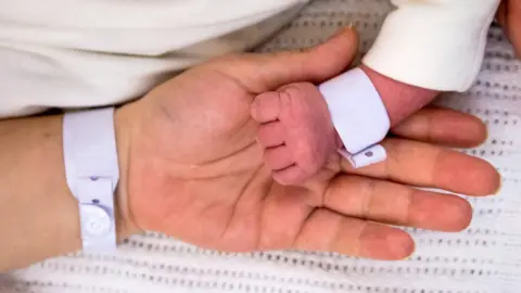 Getty Images Baby holding mother's hand