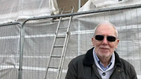 Guy Campbell/BBC Tarpaulin covering a house and mural