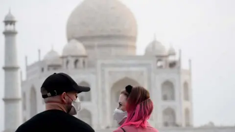 Getty Images Tourists wear face masks as a preventive measure against the spread of the COVID-19 coronavirus outbreak, near Taj Mahal in Agra on March 5, 2020