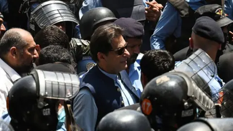 Getty Images Police commandos escort former Pakistan's Prime Minister Imran Khan (C) as he arrives at the high court in Islamabad on May 12, 2023. (Photo by Aamir QURESHI / AFP)