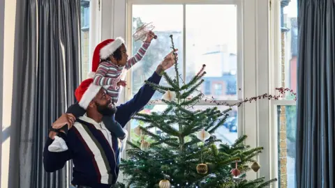 10'000 Hours A man and a girl decorate a Christmas tree