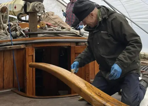 Wherry Yacht Charity A volunteer varnishing part of one of the wherries