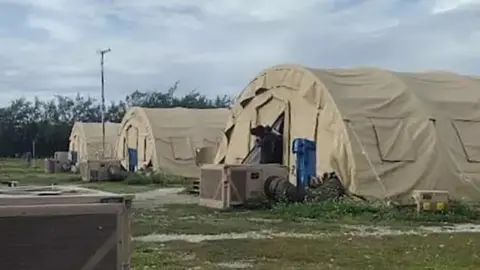 HANDOUT A low-resolution photo showing three large khaki tents used to house migrants on Diego Garcia