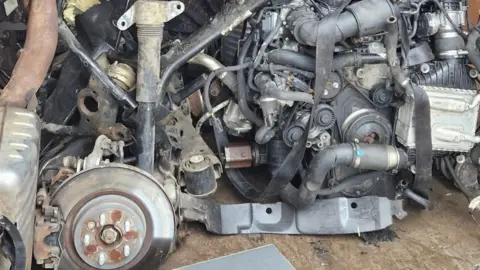 The inside of a tall van, showing metal pipes and brackets, with solid plastic and rubber objects