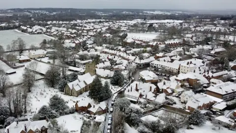 Drone footage shows the county covered in snow as a layer of white settles on homes and trees.