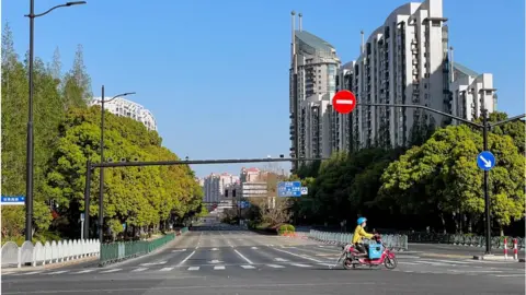 Getty Images A food delivery rider passes an empty intersection in Pudong, Shanghai, China, On April 9, 2022. Shanghai is under lockdown