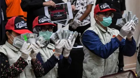 Reuters Agents show off the cash discovered inside the suitcases