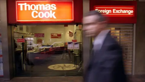 Getty Images A passerby rushes pass the British based travel retailer and foreign exchange dealer Thomas Cook which has sold it Australian and New Zealand operations, ending a 120-year-presence down under in Sydney, 12 December 2000.