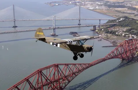 PA Jim McTaggart takes his 1940 Piper Cub, with its US Army D-Day reconnaissance aircraft markings, for a practice flight over the Forth Rail Bridge,Forth Road Bridge and the new Queensferry Crossing ahead of the aircraft"s appearance at ScotlandÕs National Airshow at East Fortune, East Lothian on Saturday 22 July.