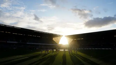 PA Media A general view inside of the New Den with the sun shining through onto the pitch where players warm up