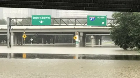 Richard Martin Flooded street below a sign to "Downtown"