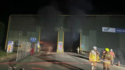 Clare Fire Station Smoke billows out of the open doors as firefighter congregate outside the building