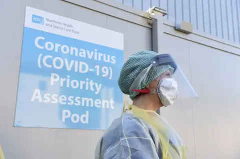 PA Media A nurse in protective equipment standing at a Covid-19 testing centre