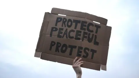 Reuters A demonstrator holds a placard during a protest against a new proposed policing bill in Bristol, Britain, March 30, 2021.