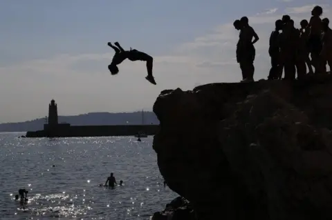 AFP Young men leap off rocks into the Meditteranean Sea at Nice, south-eastern France