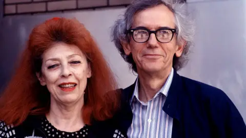 Getty Images Jeanne-Claude and Christo as they pose together at the Harlem School of the Arts, New York, 26 April 1997