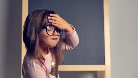 Getty Images A child holds her head