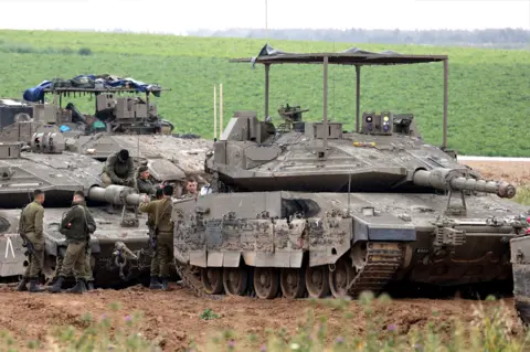 AFP Israeli army troops stand around their tanks in an area along the border with the Gaza Strip in southern Israel on 10 April 2024