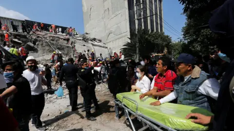 Reuters rescuers in front of a collapsed building that is right next to a building still standing, in Mexico City