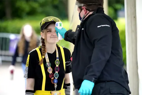 Getty Images A customer has her temperature checked