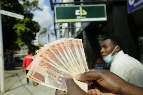 EPA A man holds a fan of the new Zimbabwe 50 dollar note in Harare.