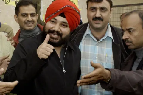Getty Images Daler Mehndi gestures at photographers as he arrives at a Delhi court on 20 December 2003.