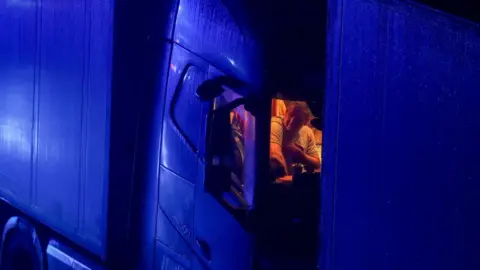 PA Media A driver sits in the cab of his lorry while parked on the M20 in Kent